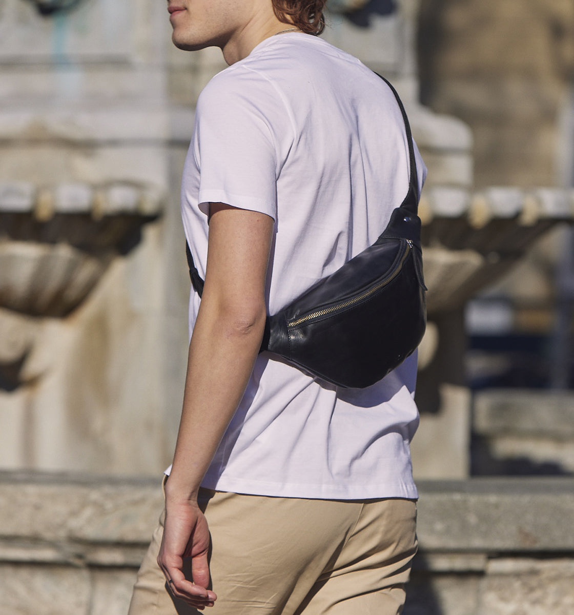 Man in white t shirt wearing black leather bum bag